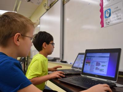 a photo of two students learning with laptops
