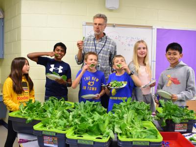a photo of students and a teacher with lettuce